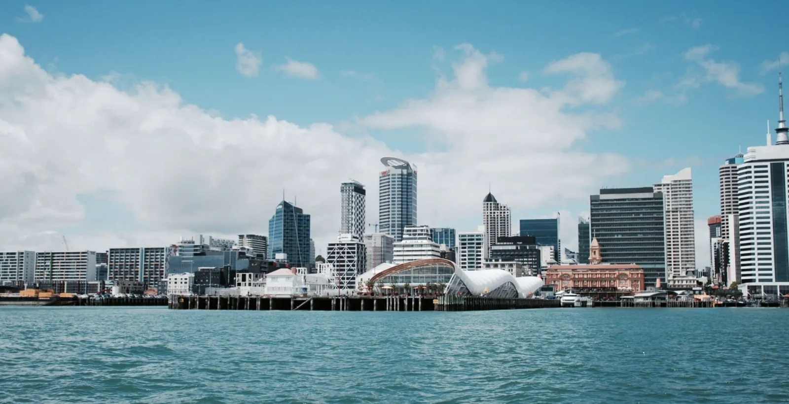 Auckland's downtown waterfront and ferry wharves seen from the harbour under scattered cloud