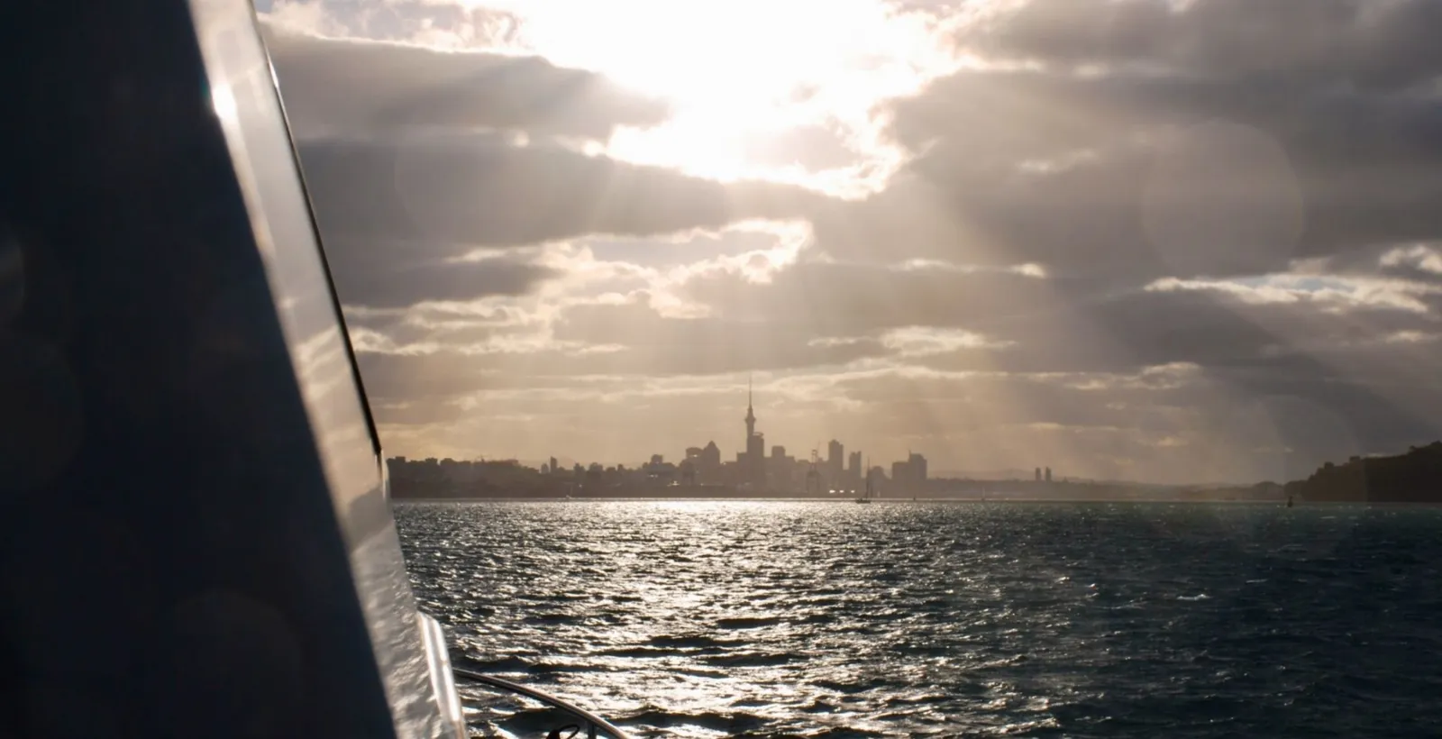 The city skyline and Sky Tower under dramatic cloud, seen past the side of a boat