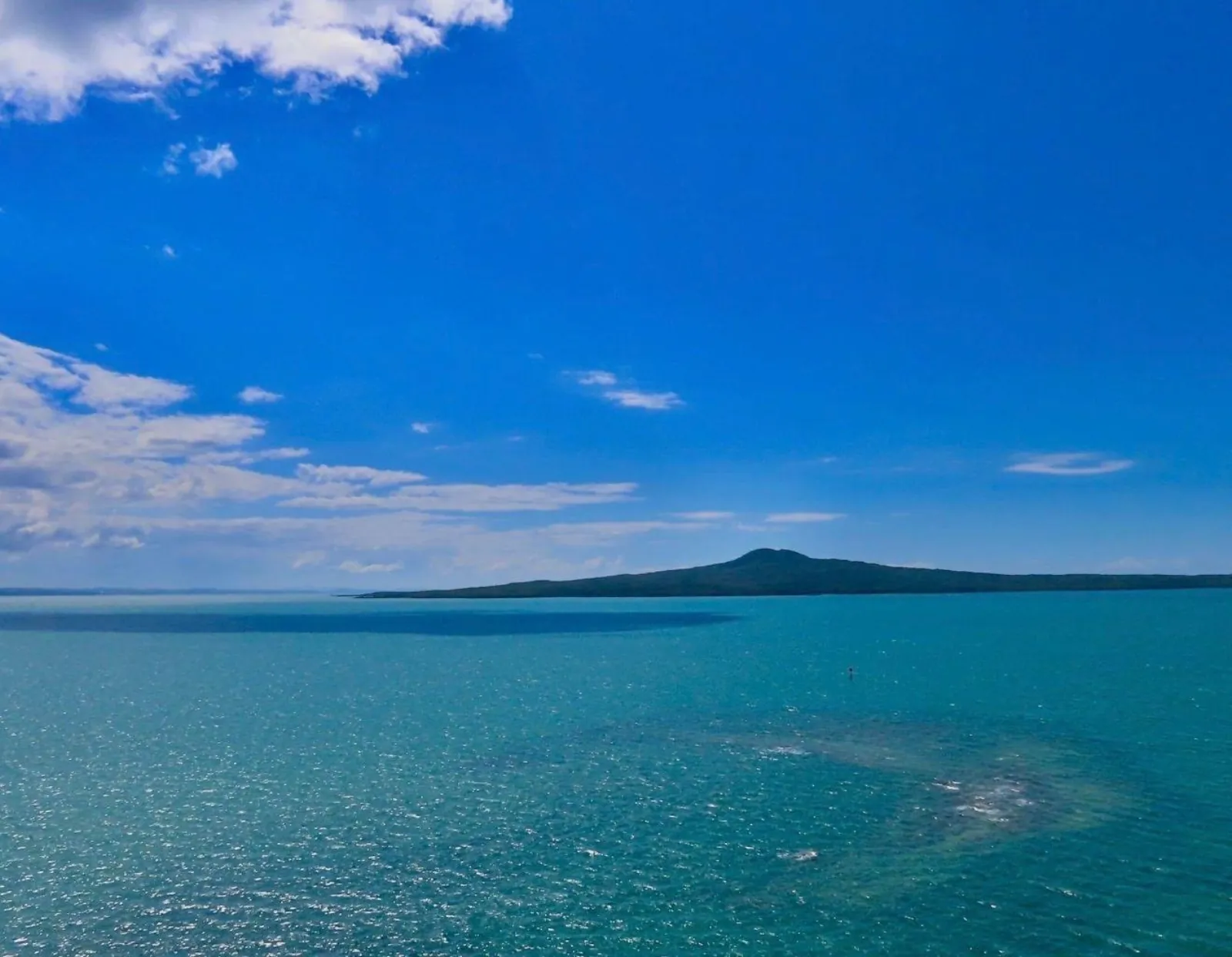 Rangitoto Island low on the horizon across bright blue water