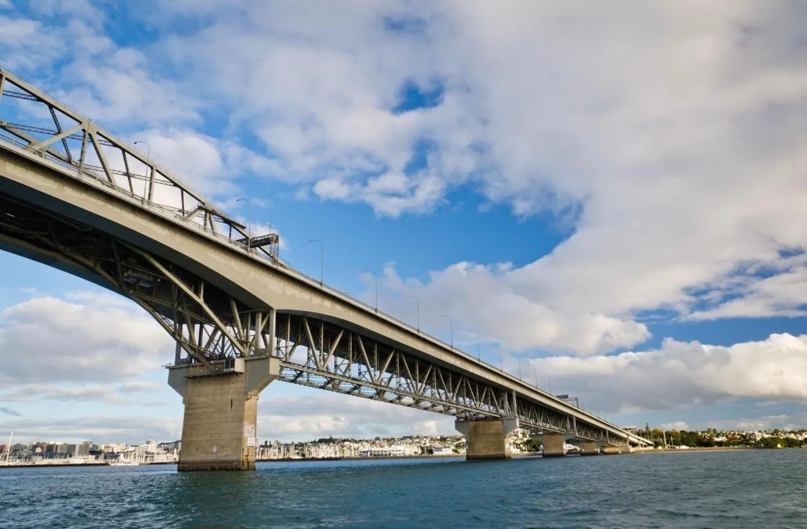Looking up at the Auckland Harbour Bridge span and concrete piers from the water