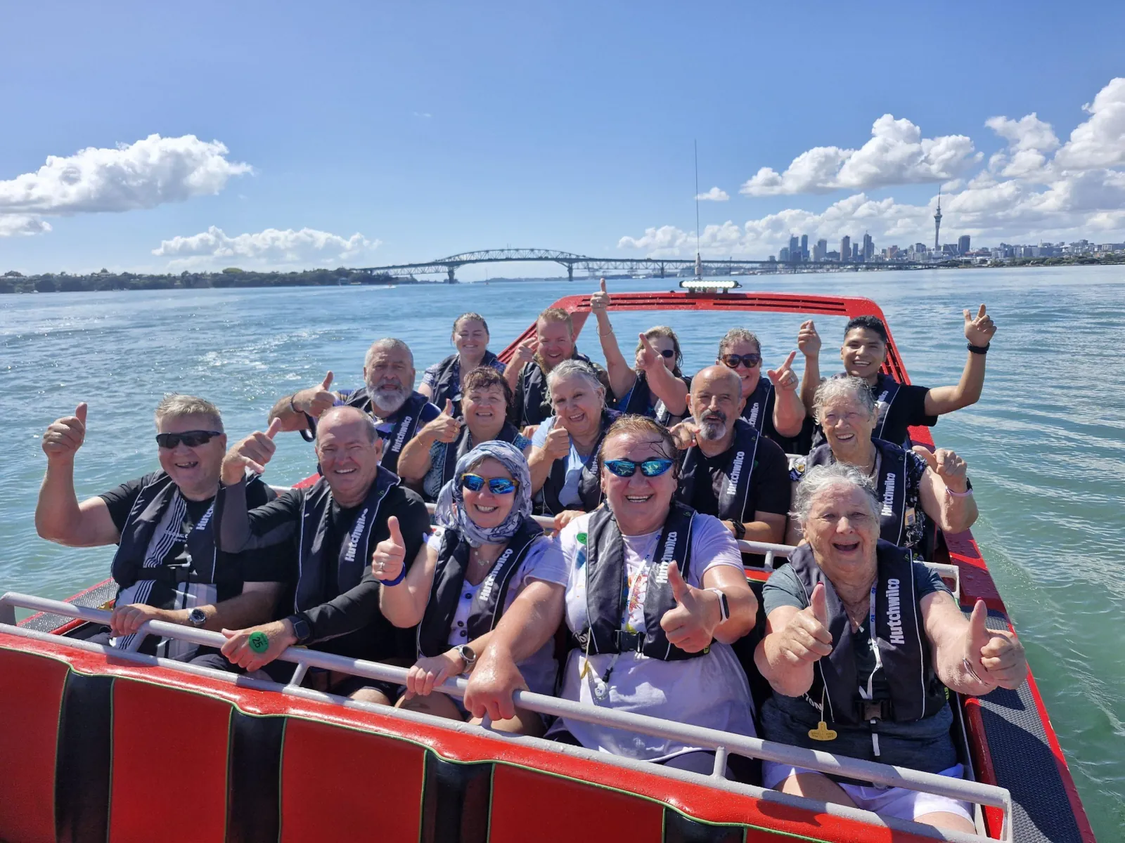 Riders in life jackets giving thumbs up with the Harbour Bridge behind