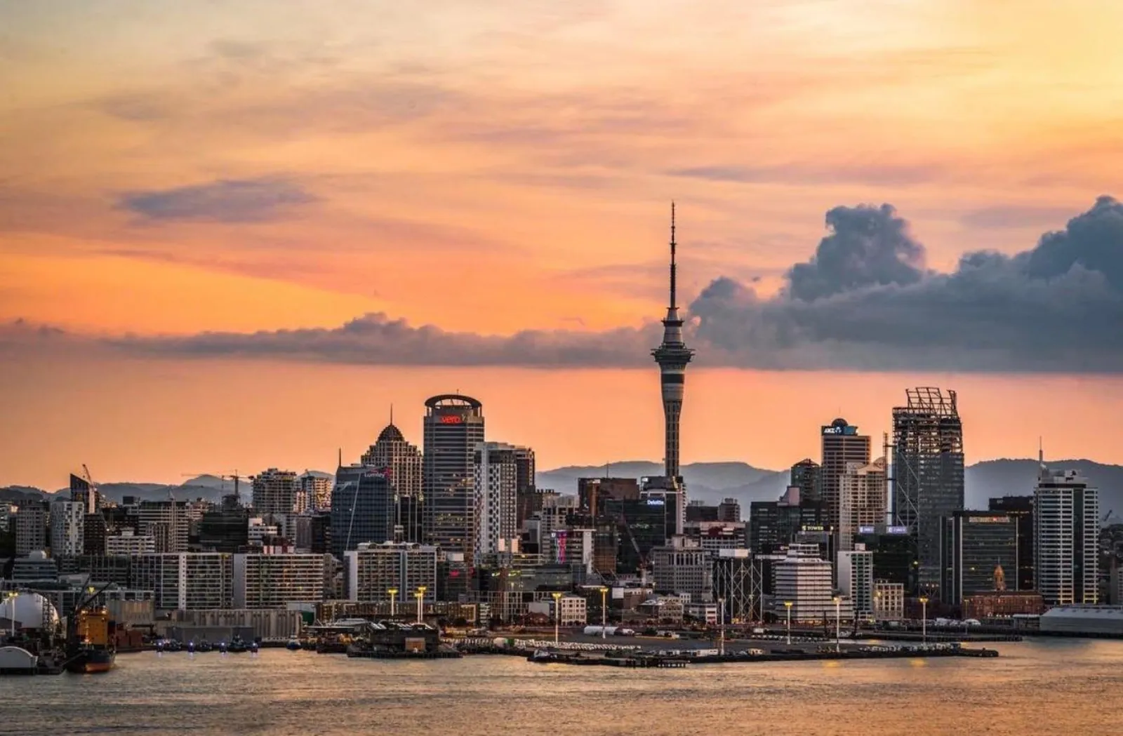 Auckland skyline and Sky Tower under a pink and orange dusk sky from the harbour