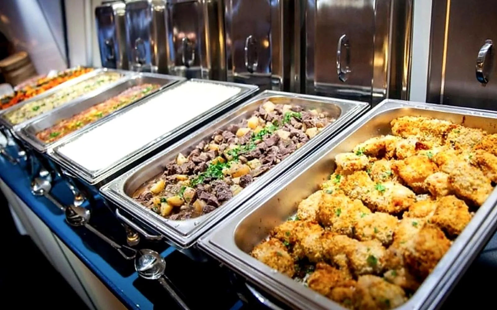 Buffet warmers of crumbed chicken, beef stir-fry and roast potatoes on board