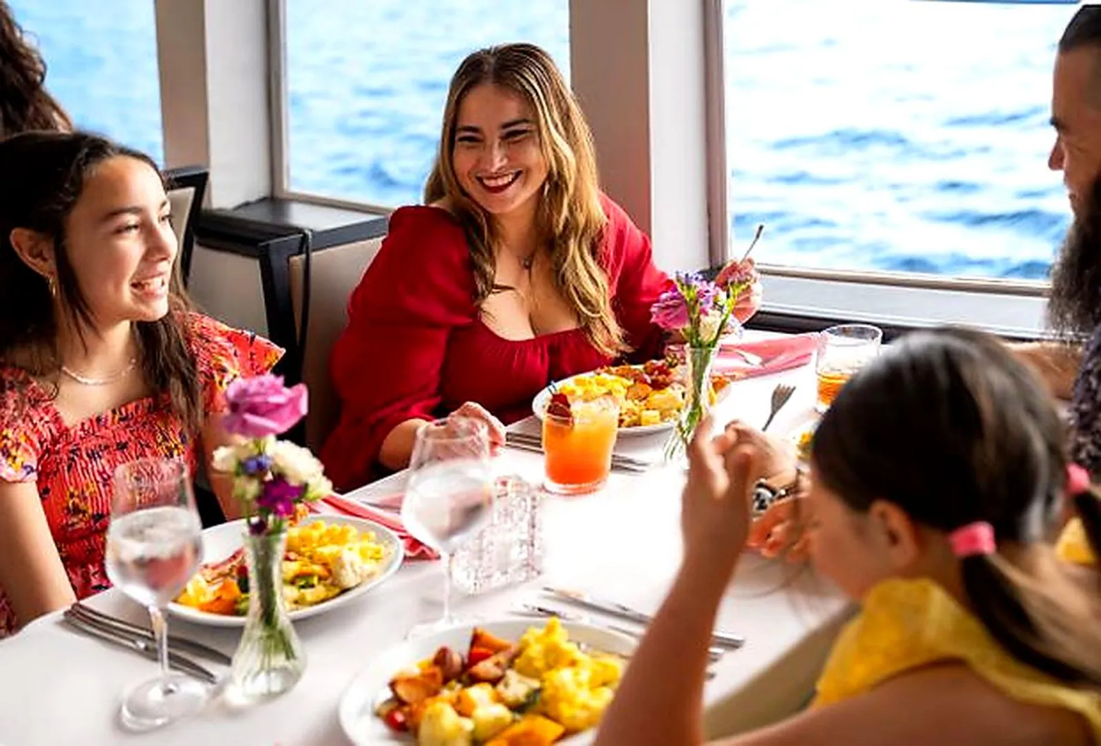 Family eating lunch at a flower-dressed table beside the boat's windows