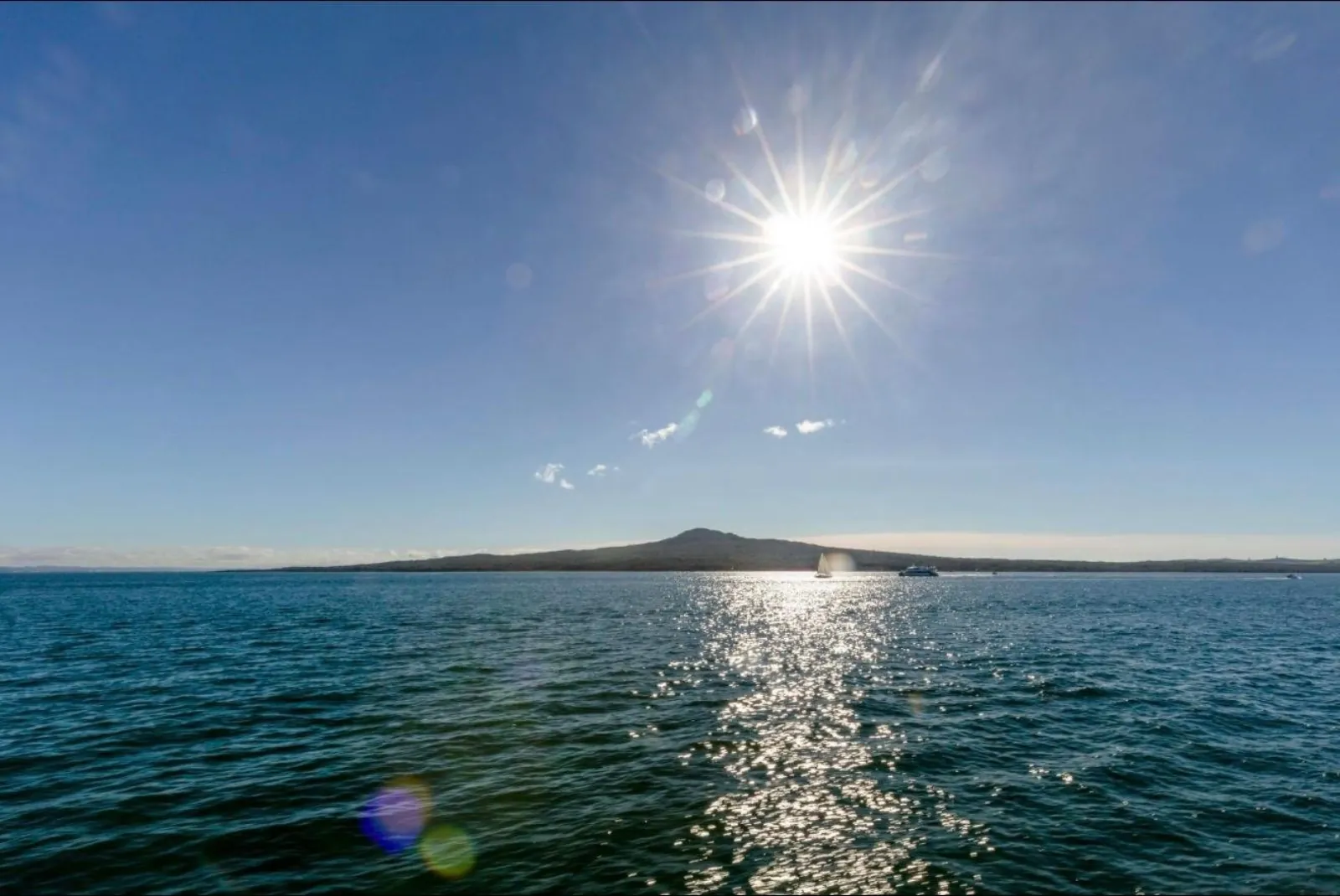 Sun sparkling on the harbour with Rangitoto Island low on the horizon