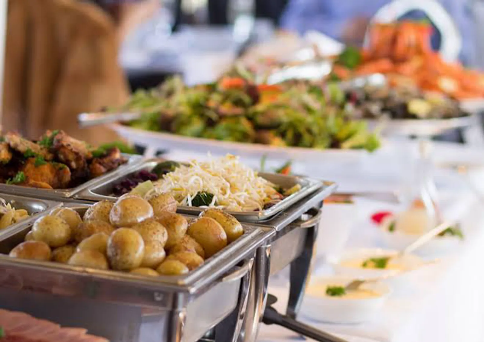 Buffet spread of salads, baby potatoes and seafood in silver chafing dishes