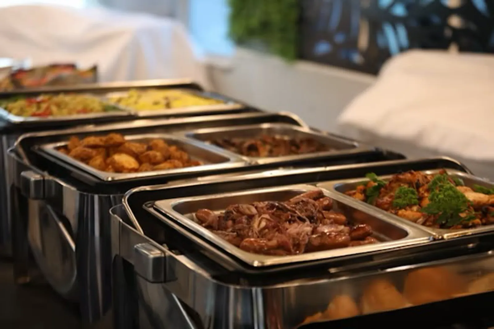 Hot buffet trays of roast potatoes, braised beef and vegetables ready to serve