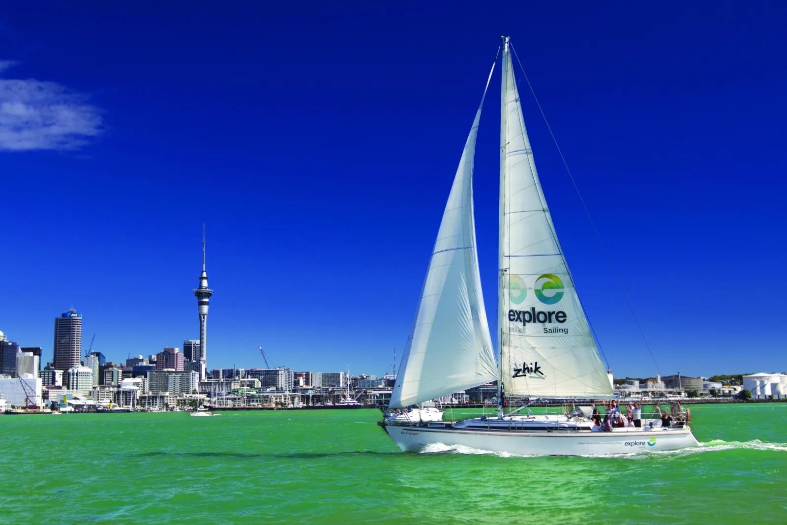 Explore Sailing cruising yacht under sail in front of the Sky Tower and skyline