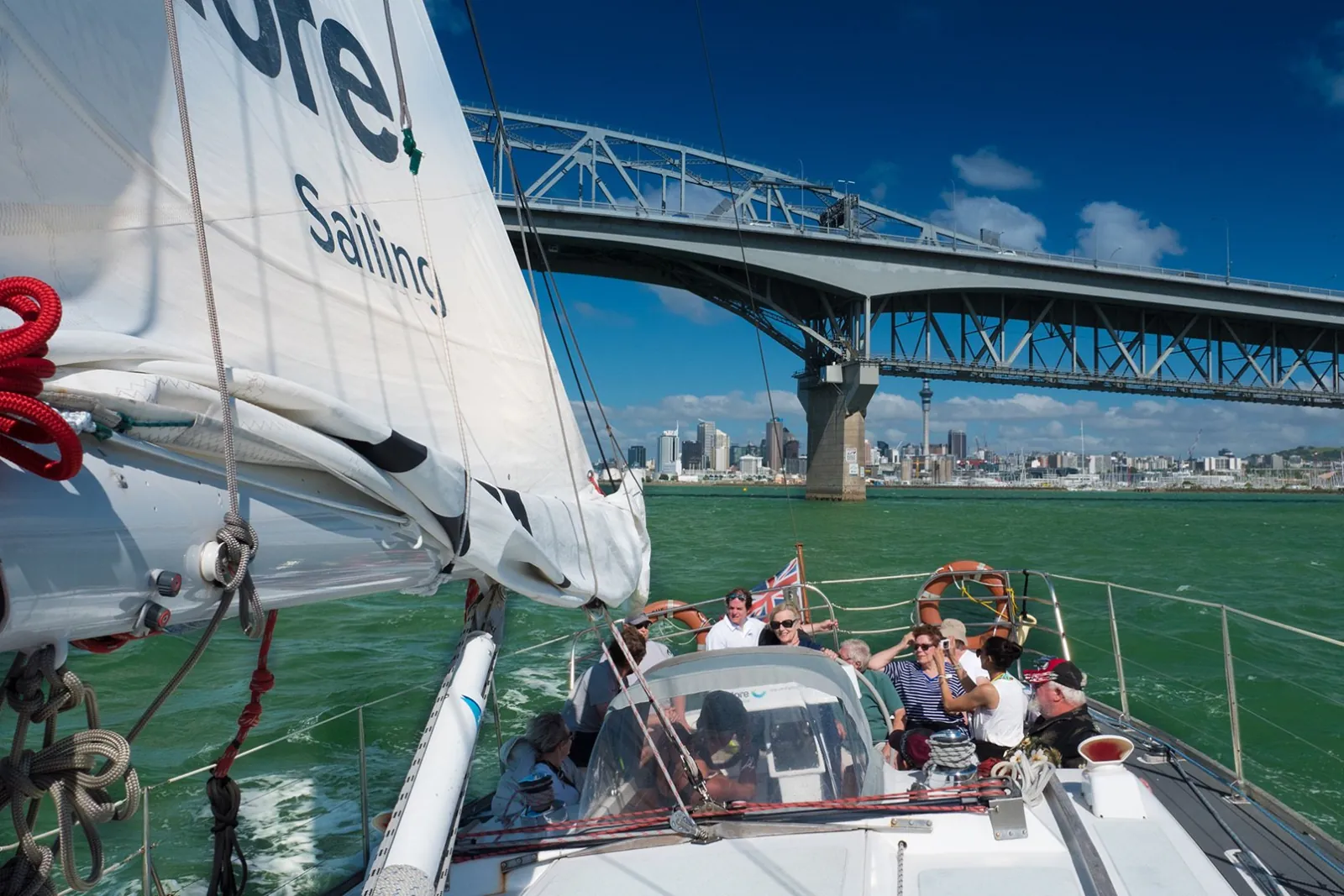 Guests relaxing in the yacht's cockpit as it approaches the Harbour Bridge