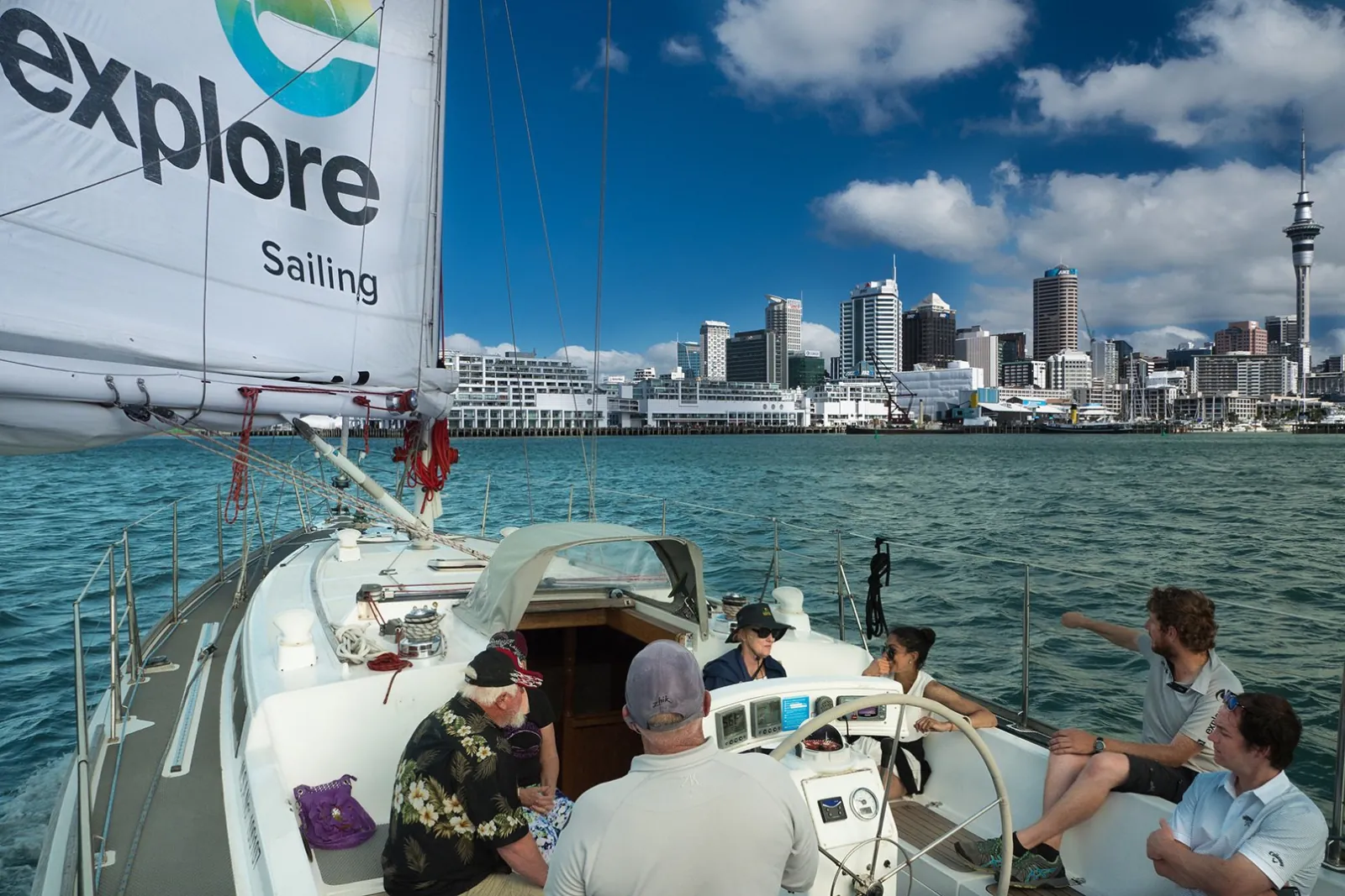 Guests seated in the cockpit as the yacht sails off the Auckland waterfront