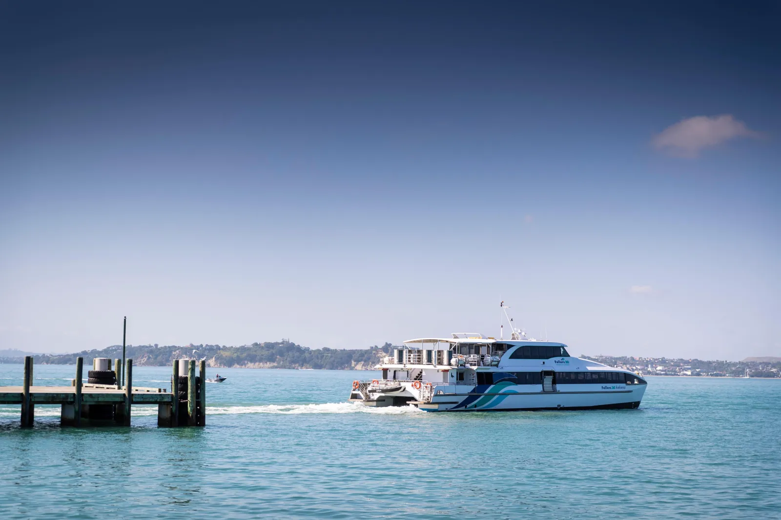 Passenger ferry approaching the Rangitoto wharf across calm blue water