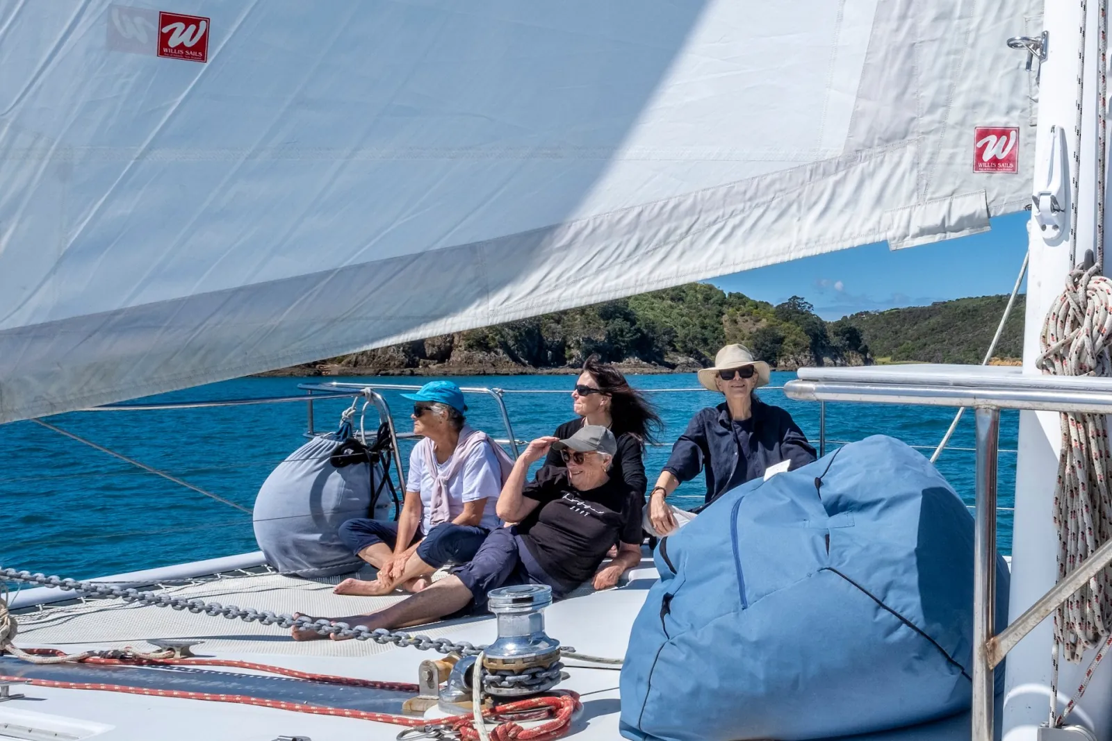 Guests relaxing on the catamaran's foredeck beanbags under the sail