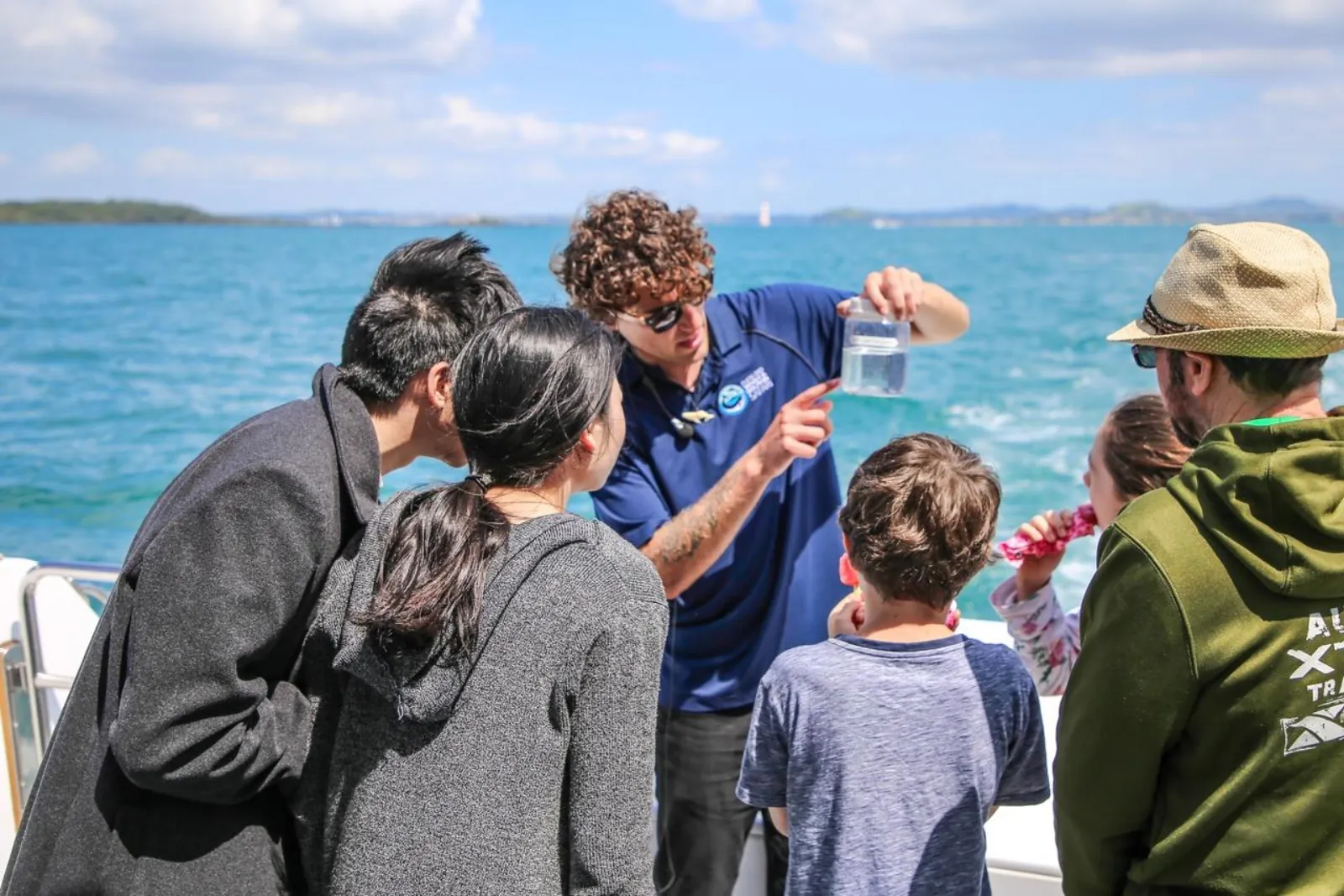 Marine researcher showing a water sample jar to passengers on deck